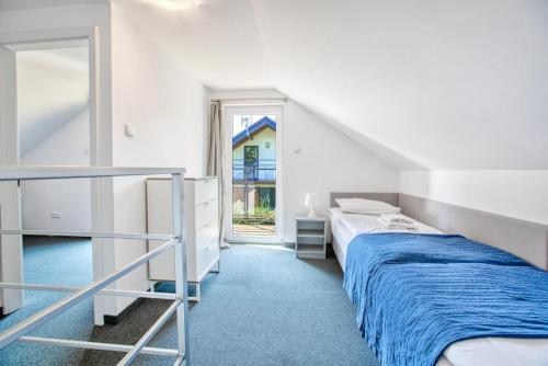 a white bedroom with a bed and a window at Domki LEŚNA POLANA in Jastrzębia Góra