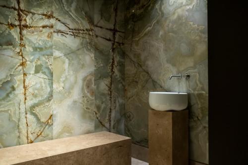 baño con lavabo y pared de mármol en Baia Di Ulisse Wellness & Spa, en San Leone