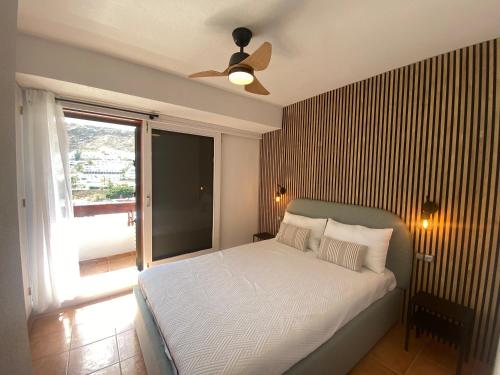 een slaapkamer met een bed, een plafondventilator en een raam bij Modern Duplex apartment near swimming pool in Mogán