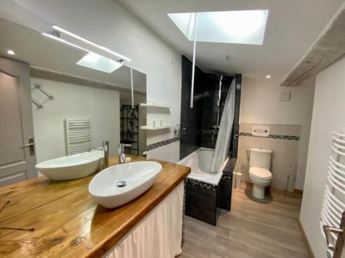 ein Badezimmer mit zwei Waschbecken, einer Badewanne und einem WC in der Unterkunft L'Escale Lauragaise in Villefranche-de-Lauragais