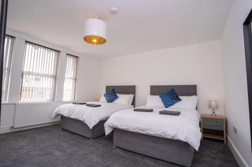 a bedroom with two beds and two windows at Luxury town apartment with roof terrace, Sleeps 6 in Blackpool