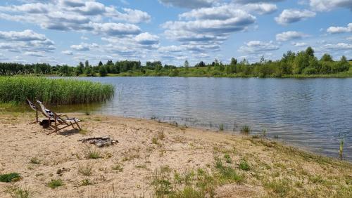 a bench sitting on the shore of a lake at Wakacyjny dom nad jeziorem 16 osób Holiday house in Szałstry