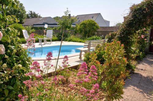 - une piscine dans un jardin avec un banc et des fleurs dans l'établissement Maison avec piscine pour 6 personnes, à Plomeur