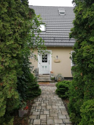 a house with a stone pathway leading to a white door at Ferienwohnung im Neubauernweg 3 in Hoppegarten