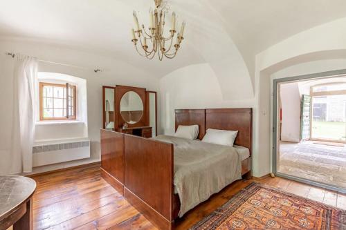 a bedroom with a bed and a mirror and a chandelier at 18 century Bohemian Farmhouse in Člunek