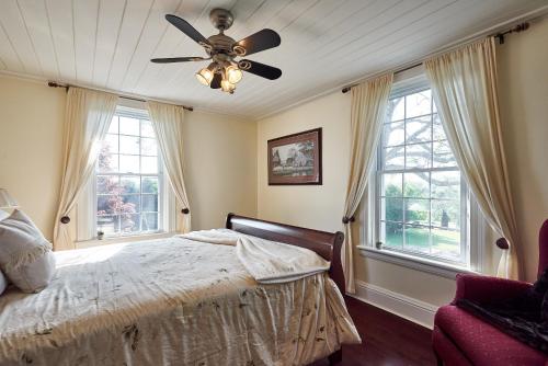 1 dormitorio con 1 cama, ventilador de techo y ventanas en Bramasole Bed and Breakfast, en Roseneath