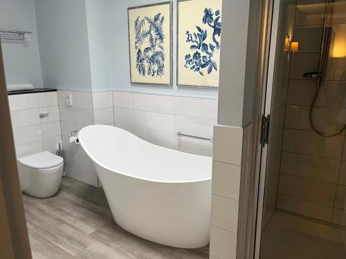a white bathroom with a tub and a toilet at Hogarths Stone Manor in Kidderminster