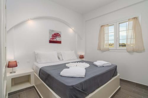 a white bedroom with a bed with two towels on it at Sunset Village 5 in Paleochori