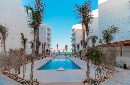 una piscina con palmeras frente a un edificio en Porto Said Tourist Resort Luxury Hotel Apartment en Port Said