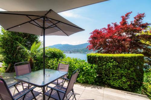 un tavolo e sedie con ombrellone e un lago di La Palma 3 by Quokka 360 - studio with terrace and lake view a Montagnola