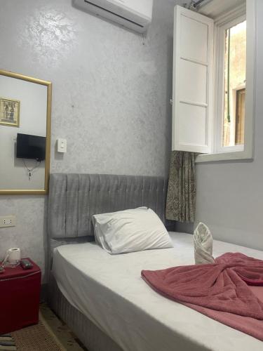 a bedroom with a bed and a window and a mirror at New One Hotel in Cairo