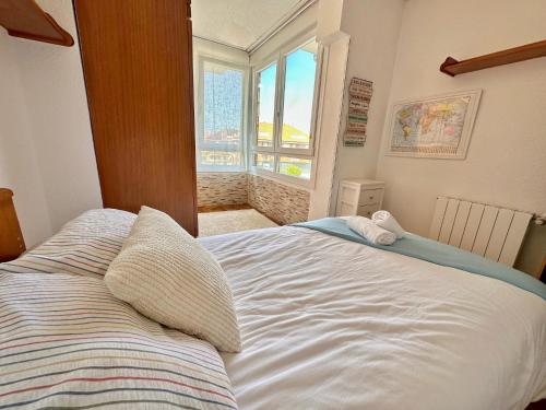 1 dormitorio con 1 cama blanca y ventana en La Marina de Ajo - 12013 en Ajo