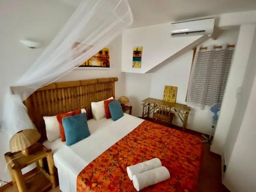 una camera da letto con un grande letto con cuscini rossi e blu di Porto Antigo - Charming & peaceful apartment overlooking pool and sea a Santa Maria