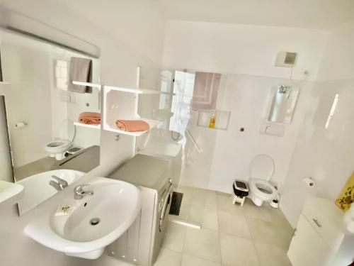 bagno bianco con lavandino e servizi igienici di Porto Antigo - Charming & peaceful apartment overlooking pool and sea a Santa Maria