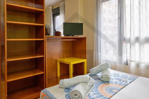 1 dormitorio con 1 cama, TV y estanterías en Loft en Oviedo - Ideal para 3 personas, en Oviedo