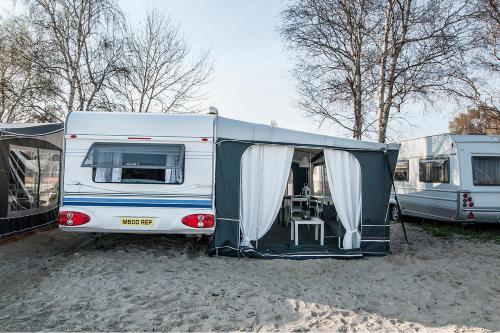 a white camper parked in a parking lot at Przyczepa w pierwszej linii brzegowej - Kemping Molo Surf in Jastarnia