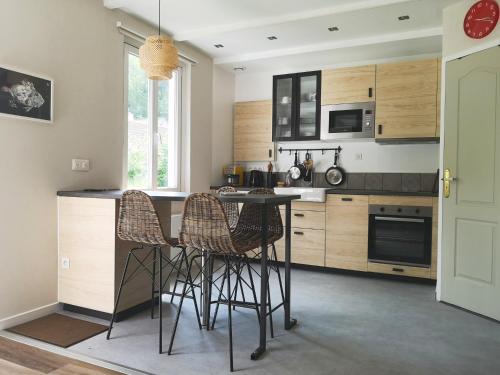uma cozinha com armários de madeira e uma mesa e cadeiras em maison au calme à Lannion entre mer et ville em Lannion