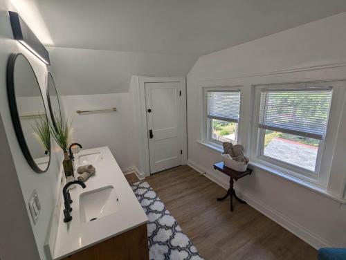 a white bathroom with a sink and two windows at Downtown Retreat - 1BR Oasis with Parking in Columbus