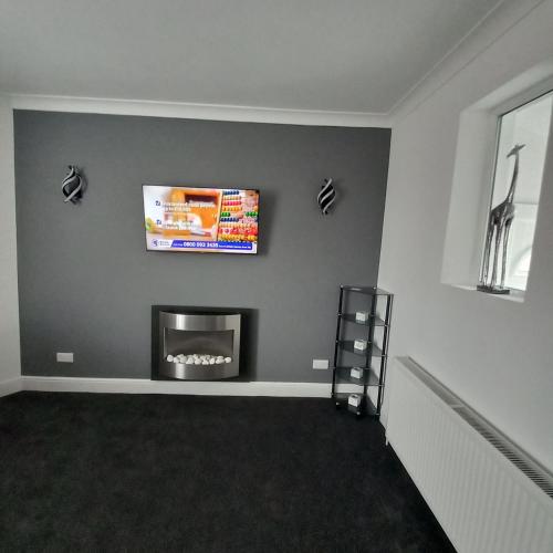 a living room with a fireplace and a tv at J & S Apartments in Ayr