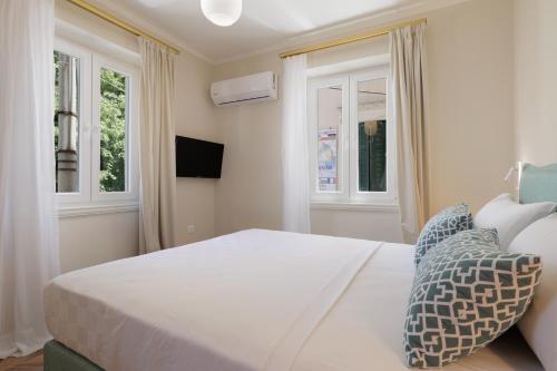 een slaapkamer met een wit bed en 2 ramen bij Piazza San Rocco Apartments in Corfu-stad