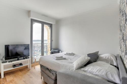 a living room with a bed and a tv at Les Ebihens - Studio et chambre indépendante in Saint-Cast-le-Guildo