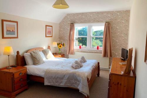 ein Schlafzimmer mit einem Bett, einem Schreibtisch und einem Fenster in der Unterkunft Manor Farm Holiday Cottages in Reighton
