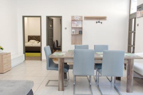 comedor con mesa de madera y sillas azules en Silver Dream Apartman, en Debrecen