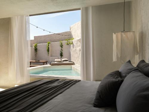 a bedroom with a bed and a swimming pool at Nomad Mykonos - Small Luxury Hotels of the World in Kalo Livadi