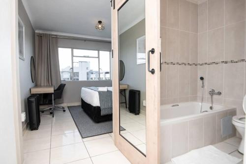 a bathroom with a bath tub and a bedroom at Unit 416 at Menlyn Place in Pretoria
