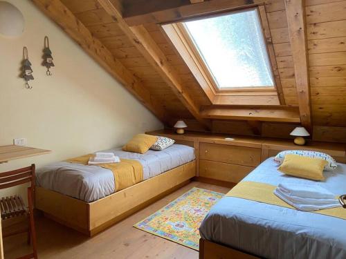two beds in a room with a window at Vacanza da sogno nell’Altopiano. in Gallio
