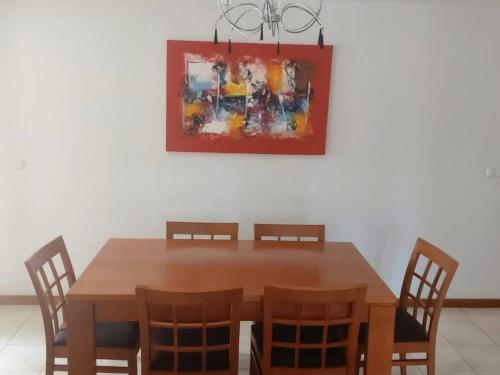 una mesa de comedor con sillas y una pintura en la pared en Apartamento acolhedor na Cidade da Praia, en Praia