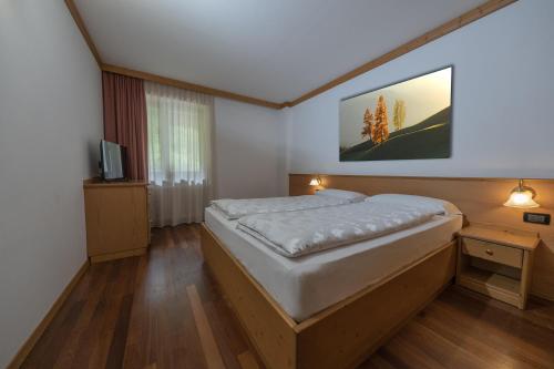 1 dormitorio con 1 cama grande y TV en Residence Kristall- Fiemme Holidays, en Predazzo