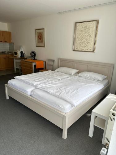 Cette chambre comprend un grand lit blanc et une cuisine. dans l'établissement FeWo Hamel, à Kehl