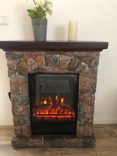 a stone fireplace with a fire in it at Bungalow-Am-Eichholz in Ilsenburg