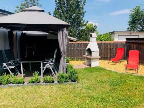 a gazebo with chairs and a grill in a yard at Bungalow-Am-Eichholz in Ilsenburg