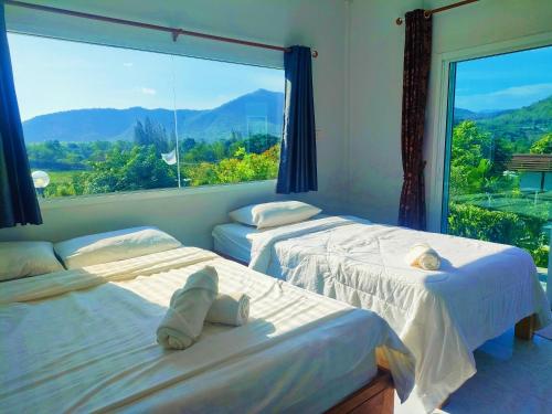 two beds in a room with a large window at Baan Mai Hom Resort Suan Phueng in Suan Phung