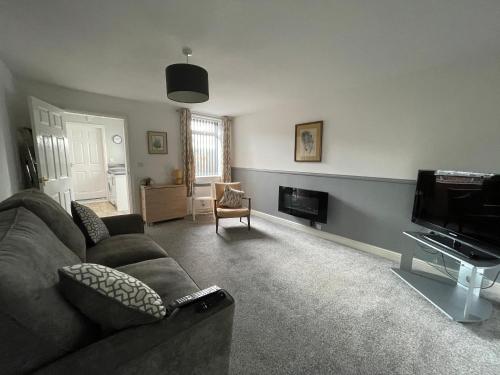 a living room with a couch and a television at Cosy & Comfortable Apartment w/Parking in Worksop