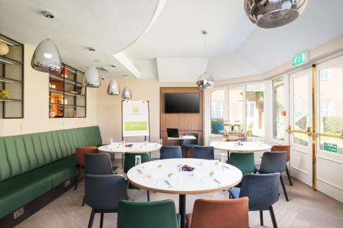 a restaurant with tables and chairs and a screen at Holiday Inn Reading West by IHG in Reading