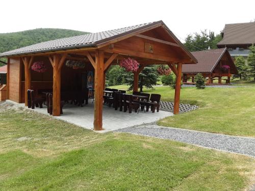 a wooden pavilion with tables and chairs in a park at Górska Hacjenda in Brenna