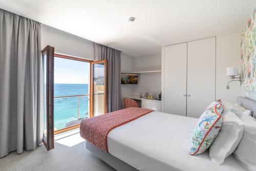 a bedroom with a bed and a view of the ocean at Castelo Guest House in Carvoeiro