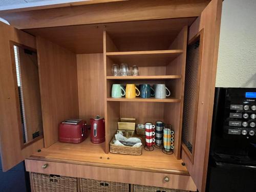 a cupboard with coffee mugs and a microwave at Flag Hotel Lisboa Oeiras in Oeiras