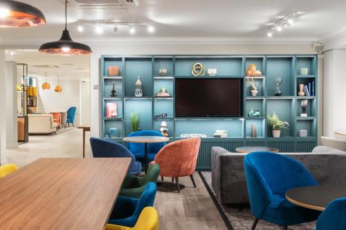 une salle d'attente avec des chaises bleues et une télévision à écran plat dans l'établissement Holiday Inn Derby/Nottingham, an IHG Hotel, à Derby