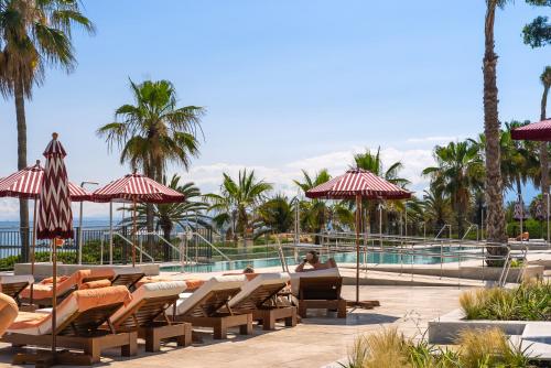 a resort with a pool and people sitting on chairs and umbrellas at El Fuerte Marbella in Marbella