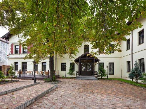 a large white building with a brick driveway at Hotel Braník in Prague