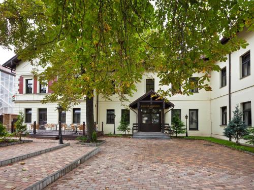 duży biały budynek z ceglanym podjazdem w obiekcie Hotel Braník w Pradze