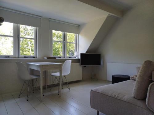 sala de estar con sofá, mesa y ventanas en Vince appartement Culemborg en Kuilenburg