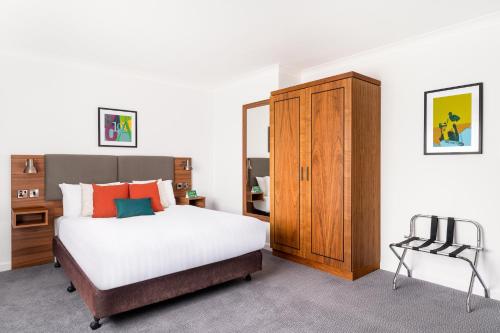 ブロムスグローブにあるHoliday Inn Birmingham Bromsgrove, an IHG Hotelのベッドルーム1室(ベッド1台、キャビネット、椅子付)