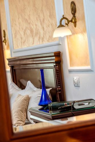 a blue vase sitting on a bed in front of a mirror at Hotel Victoria in Piteşti