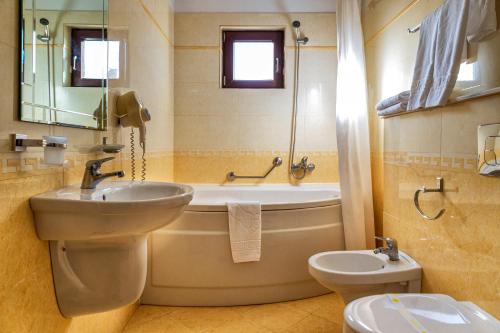 a bathroom with a sink and a tub and a toilet at Hotel Victoria in Piteşti