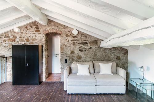 Sofá blanco en una habitación con pared de piedra en Casa Brocchi by Quokka 360 - unique design house with garden, en Sorengo